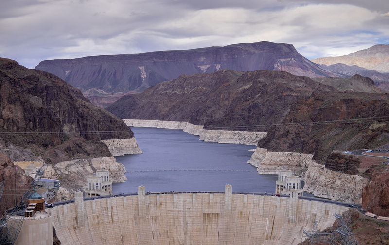 Scenic view of dam and mountains against sky
