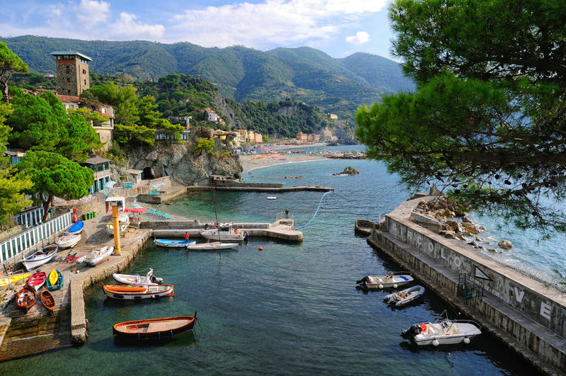 Boats moored at harbor by monterosso al mare town against mountains