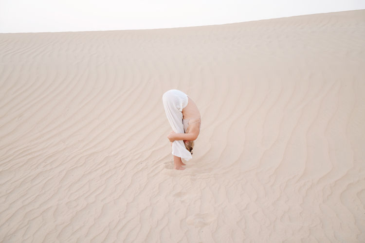 Woman in the desert doing forward fold