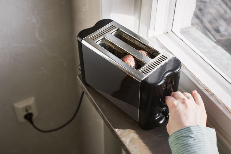 Hands putting toasts inside toaster