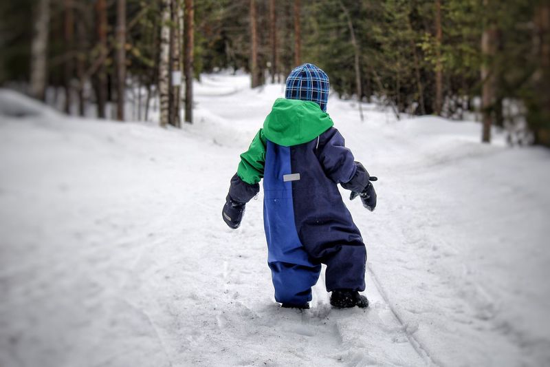 Rear view of boy walking in snow