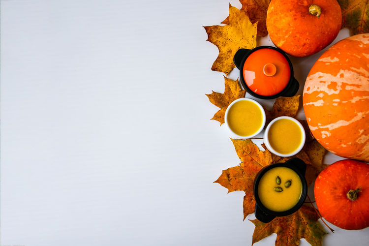 Autumn food. frame of pumpkin puree soup, leaves. top view. autumn harvest, pumpkins, leaves on grey 