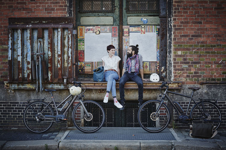 People sitting on bicycle against brick wall