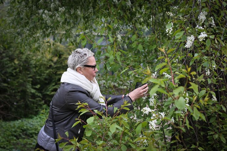 Side view of mature woman photographing plants at park