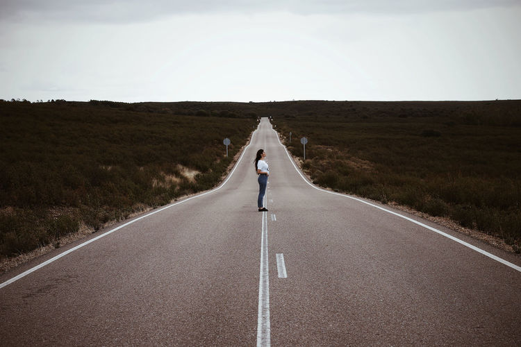 Young spanish girl, in the middle of a lonely road, during summer.