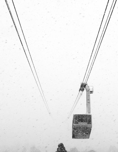 Low angle view of overhead cable car against clear sky during winter