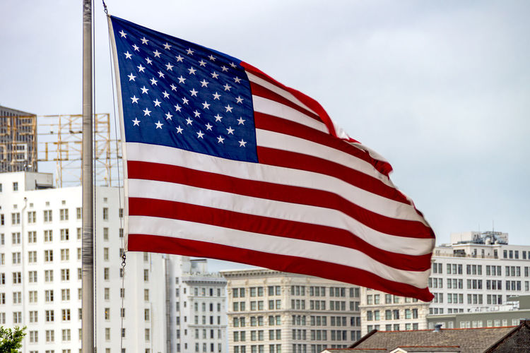 View of american flag against sky in city