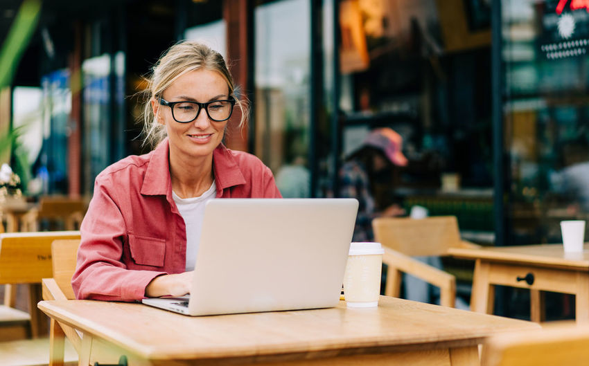 Young attractive caucasian woman sitting in a cafe works on a laptop