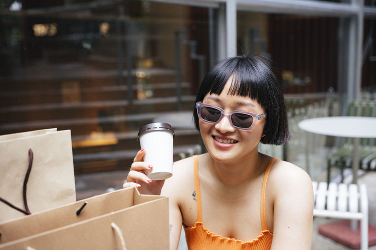Lesbian woman holding disposable coffee cup sitting at cafe