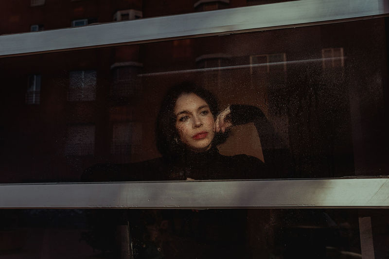 Portrait of young woman looking through window