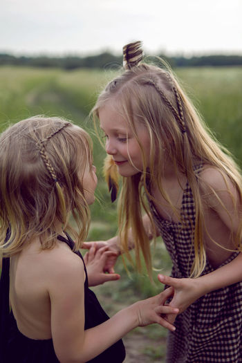 Two sisters blondes in a field are played in indians in summer