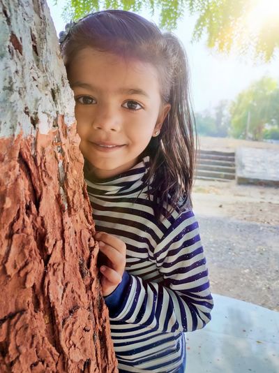 Portrait of smiling girl standing against tree