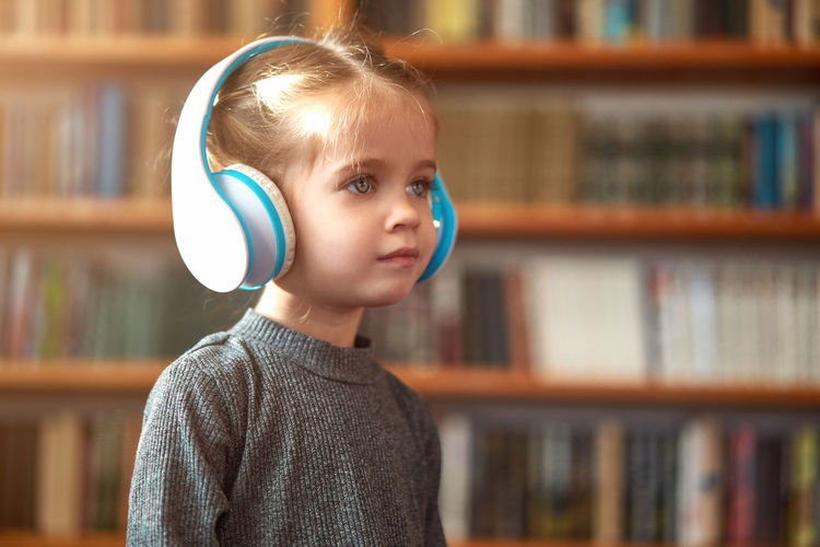 Cute girl listening music through headphones at home