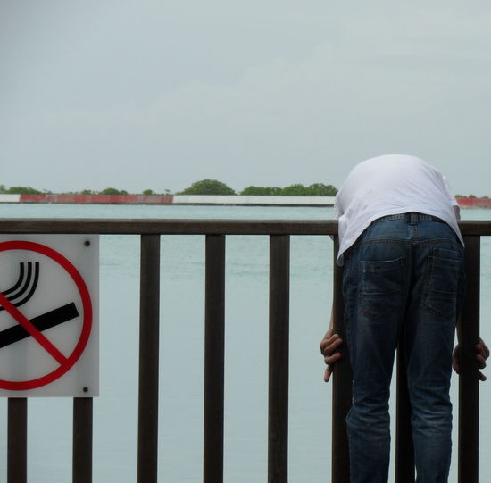 Midsection of man bending on railing against river