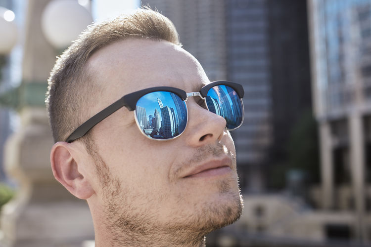 Reflection of skyscrapers in sunglasses of young man. tourist admiring historical buildings in city. 