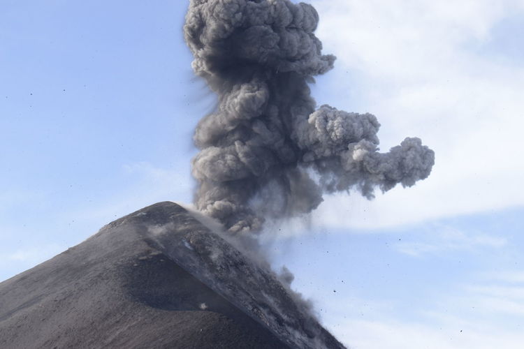 Close-up of smoke stack on volcanic mountain against sky