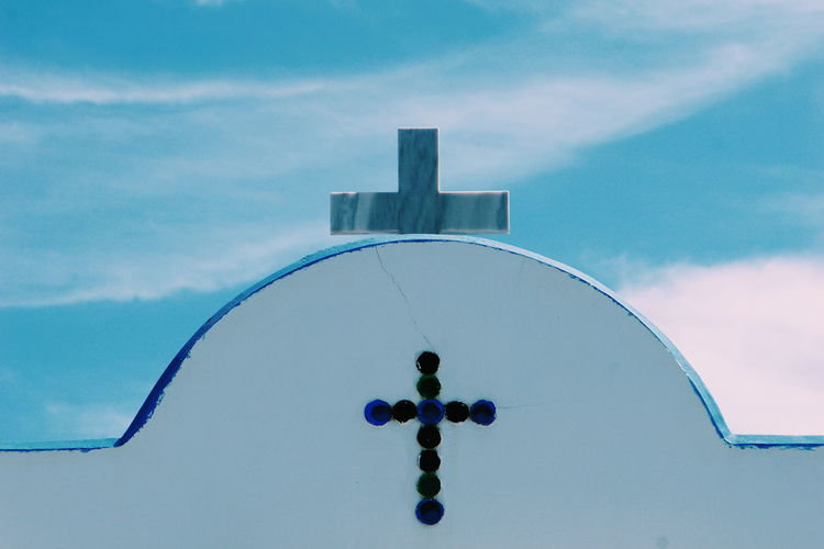 Low angle view of cross on building against sky