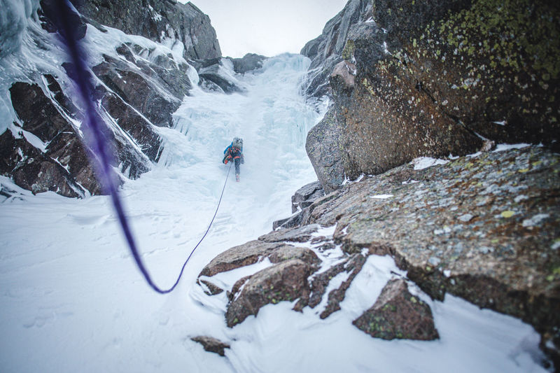 An ice climber climbs up a steep gully full of ice in maine alpine