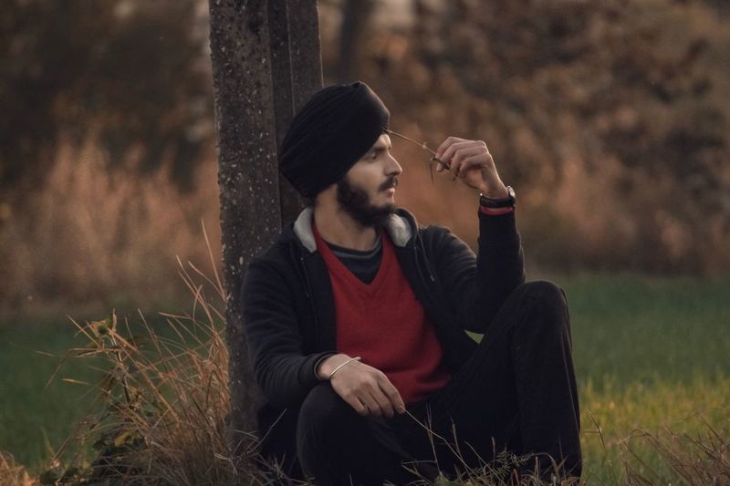 Thoughtful young man sitting on field