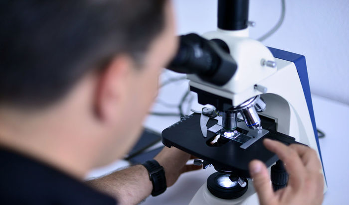 Close-up of male scientist looking through microscope at laboratory