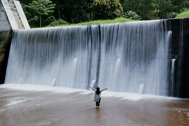 Man standing by waterfall