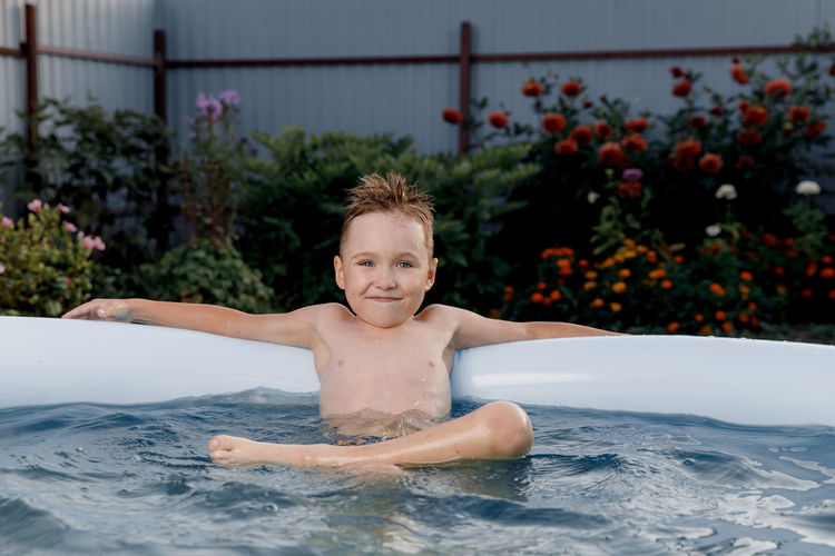 Portrait of smiling boy sitting in wading pool