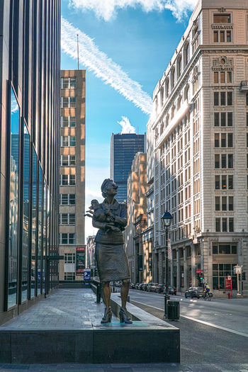 View of statue by street against buildings in city