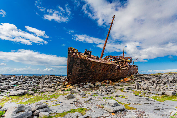 Old abandoned cargo ship plassey on the beach against blue sky, ship that wrecked on the rocky beach