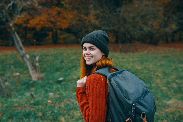Portrait of smiling young woman standing on land during autumn