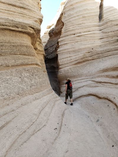 Rear view of woman walking by rock formation