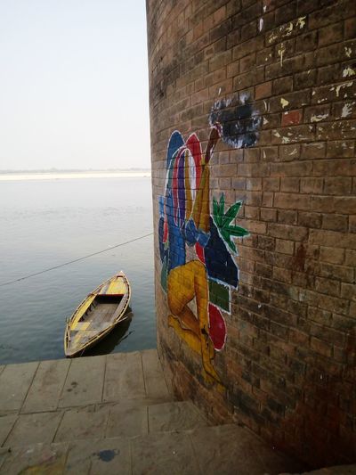 Graffiti on wall by sea against clear sky