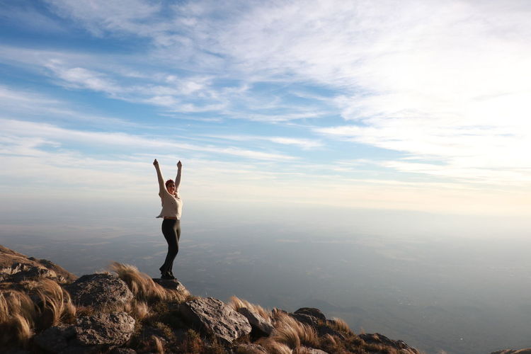 Woman with arms outstretched standing on mountain
