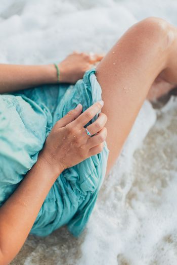 Low section of woman wearing shoes on beach