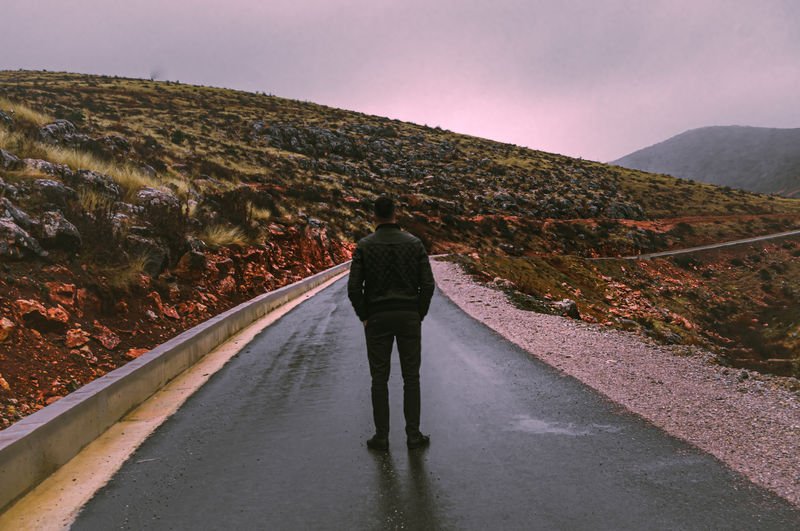 Rear view of woman walking on road against sky