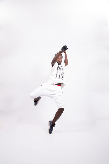 Full length of young man jumping against white background