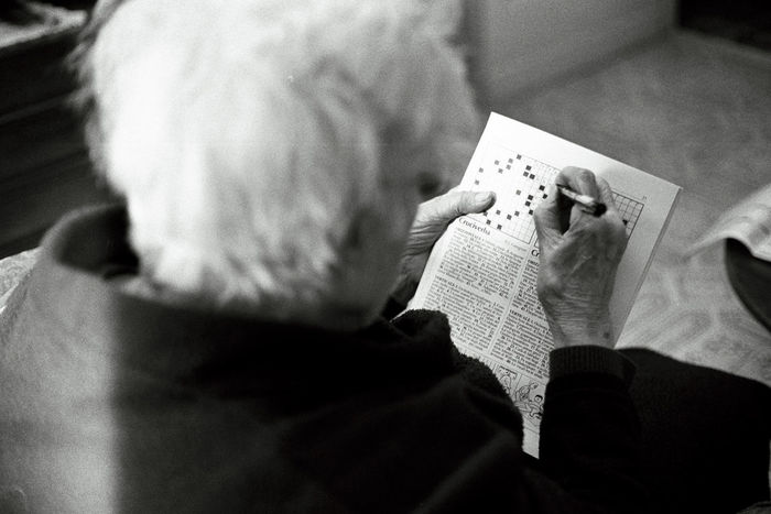 High angle view of senior woman solving crossword puzzle