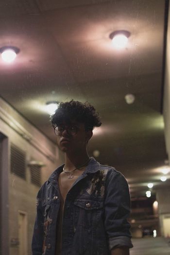 Young man standing against illuminated light indoors