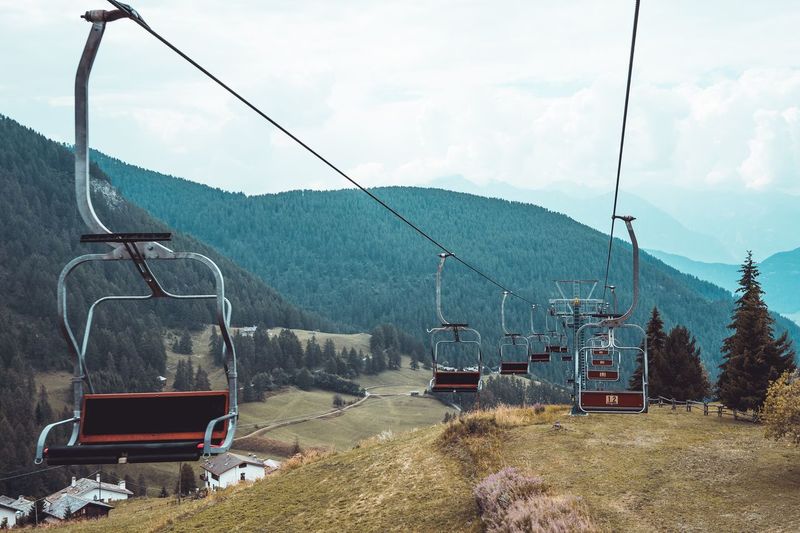 Ski lifts over mountains against sky