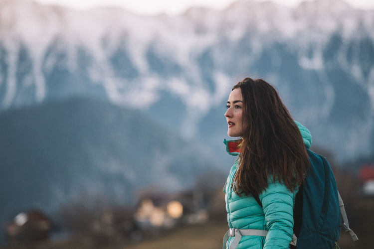 Woman hiking in winter and admiring the amazing view towards the mountains in sunset light.