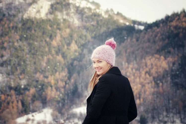 Portrait of smiling woman standing against mountain during winter