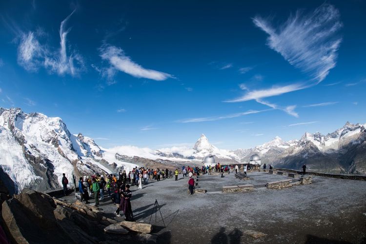 People on mountain against blue sky