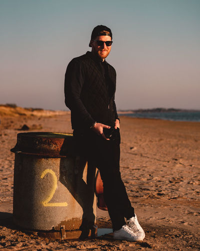 Full length of young man wearing sunglasses standing at beach