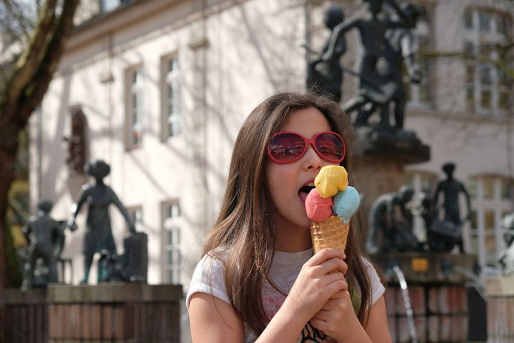 Girl eating ice cream cone in city
