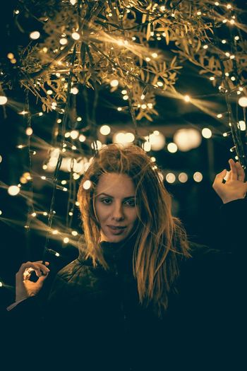 Portrait of woman with illuminated string lights at night