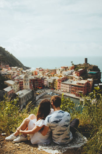 Rear view of couple looking at cityscape against sky
