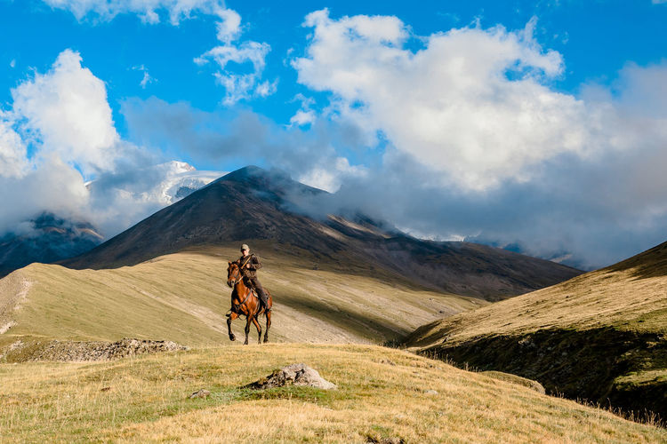 Rear view of man walking on mountain against sky
