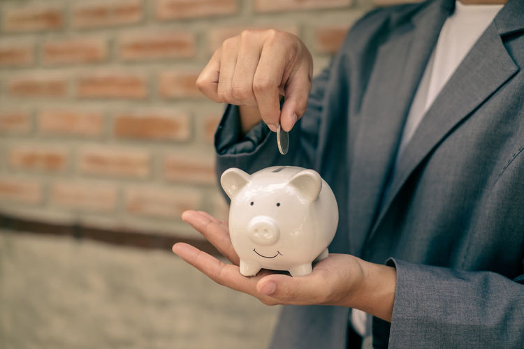 Midsection of businessman holding piggy bank