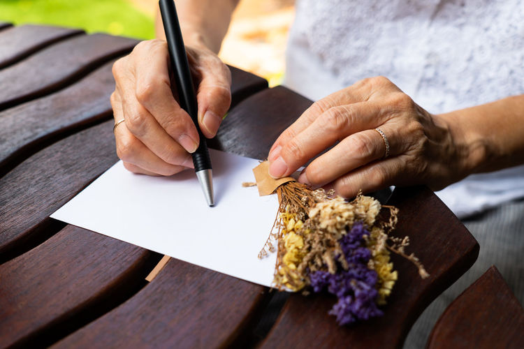 Close-up of woman writing on card at table