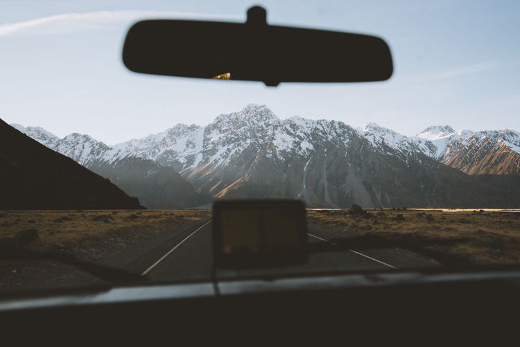 Snowcapped mountains seen through car windshield