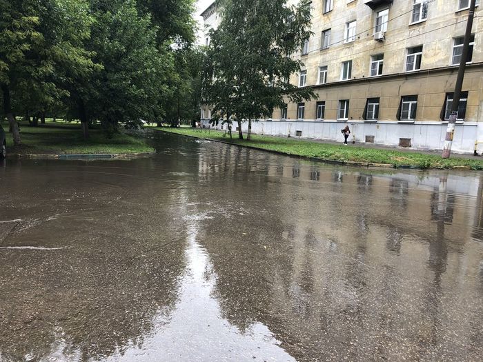 Wet street amidst buildings in city